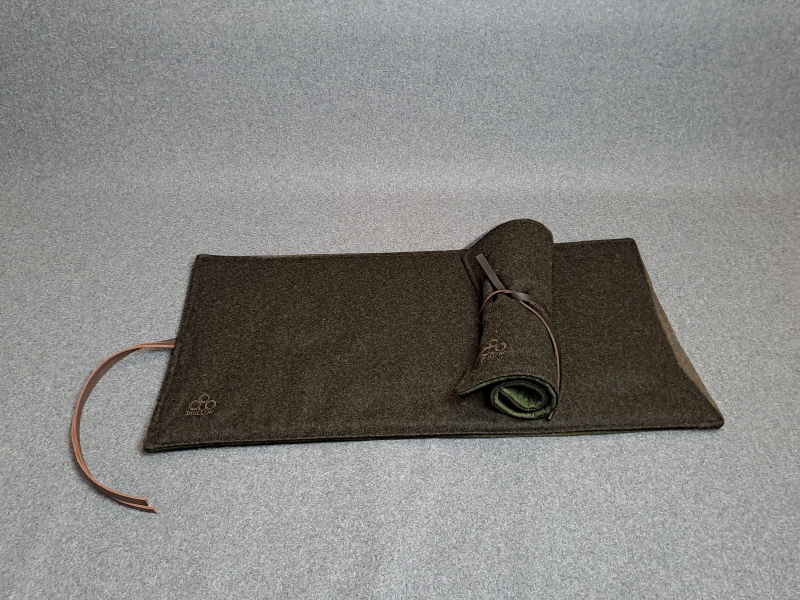 Großes braunes Loden-Sitzkissen mit aufgerolltem kleinem Sitzkissen und Hirschlederbändern.